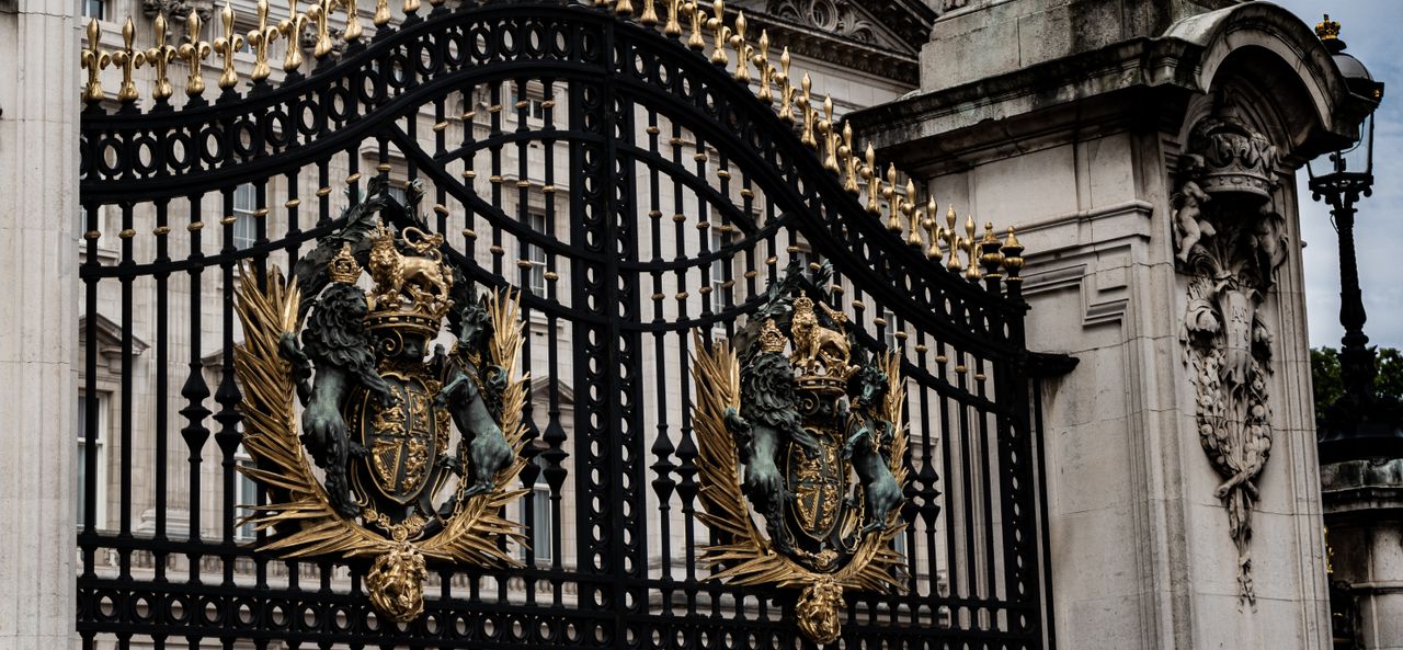 A detailed view of the ornate iron gate with royal crests at Buckingham Palace, London.